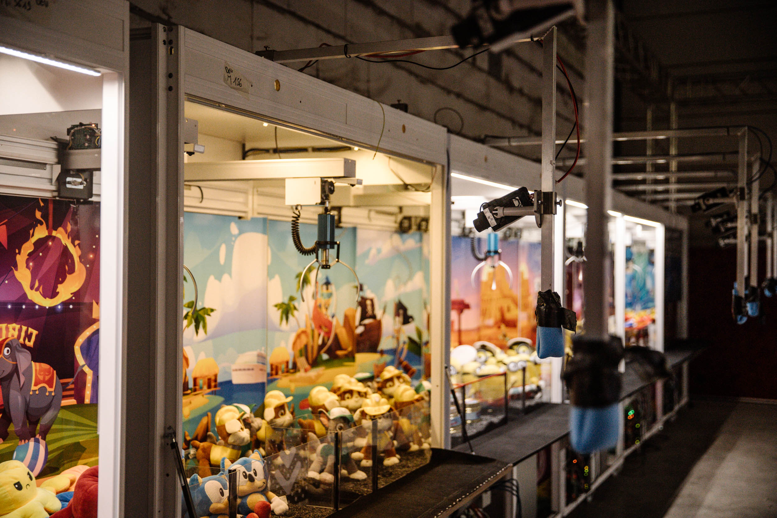 Claw machines in an arcade environment with cameras above them to stream live.